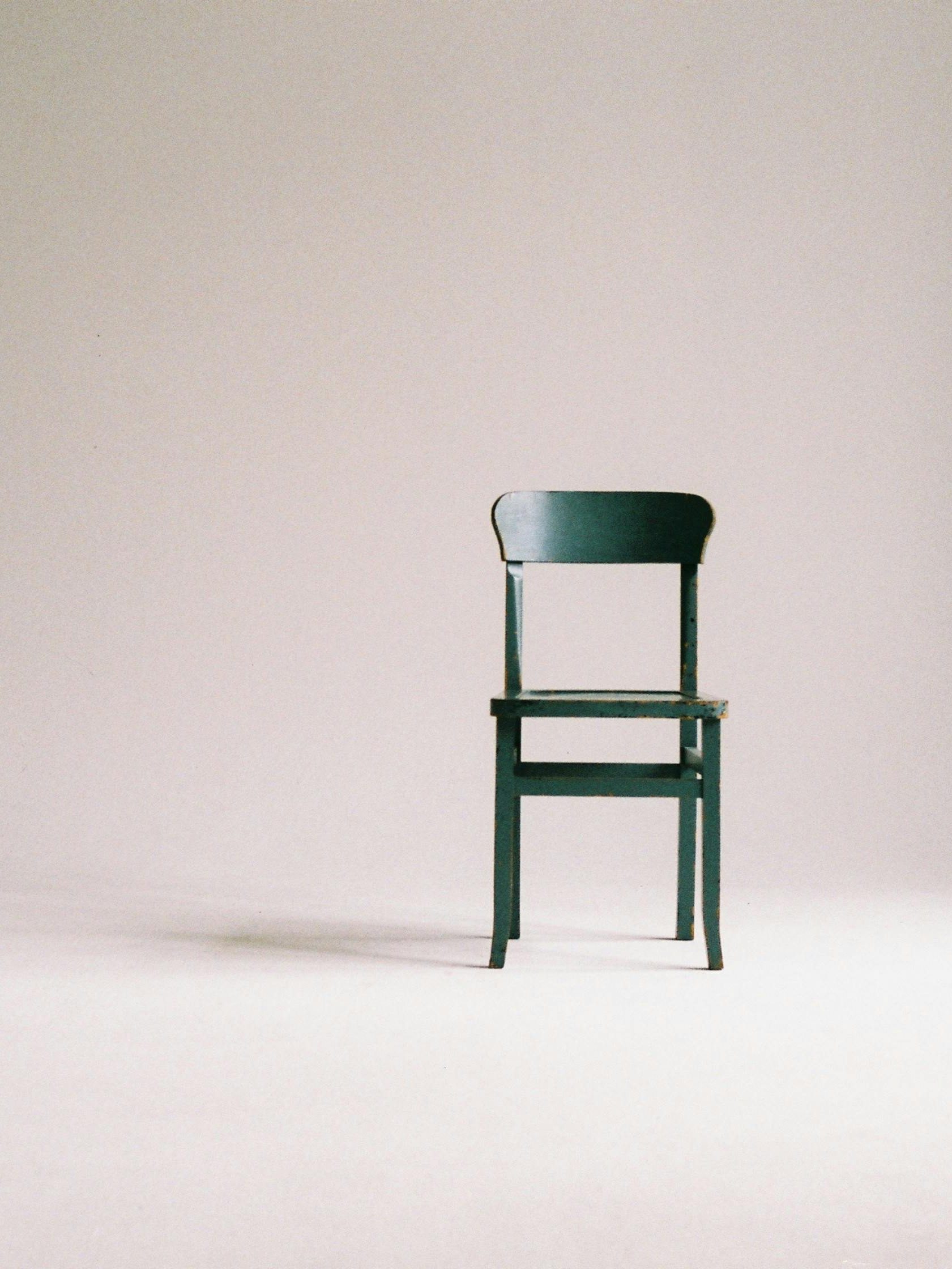 A single black chair in a minimalistic studio setting with a neutral backdrop.