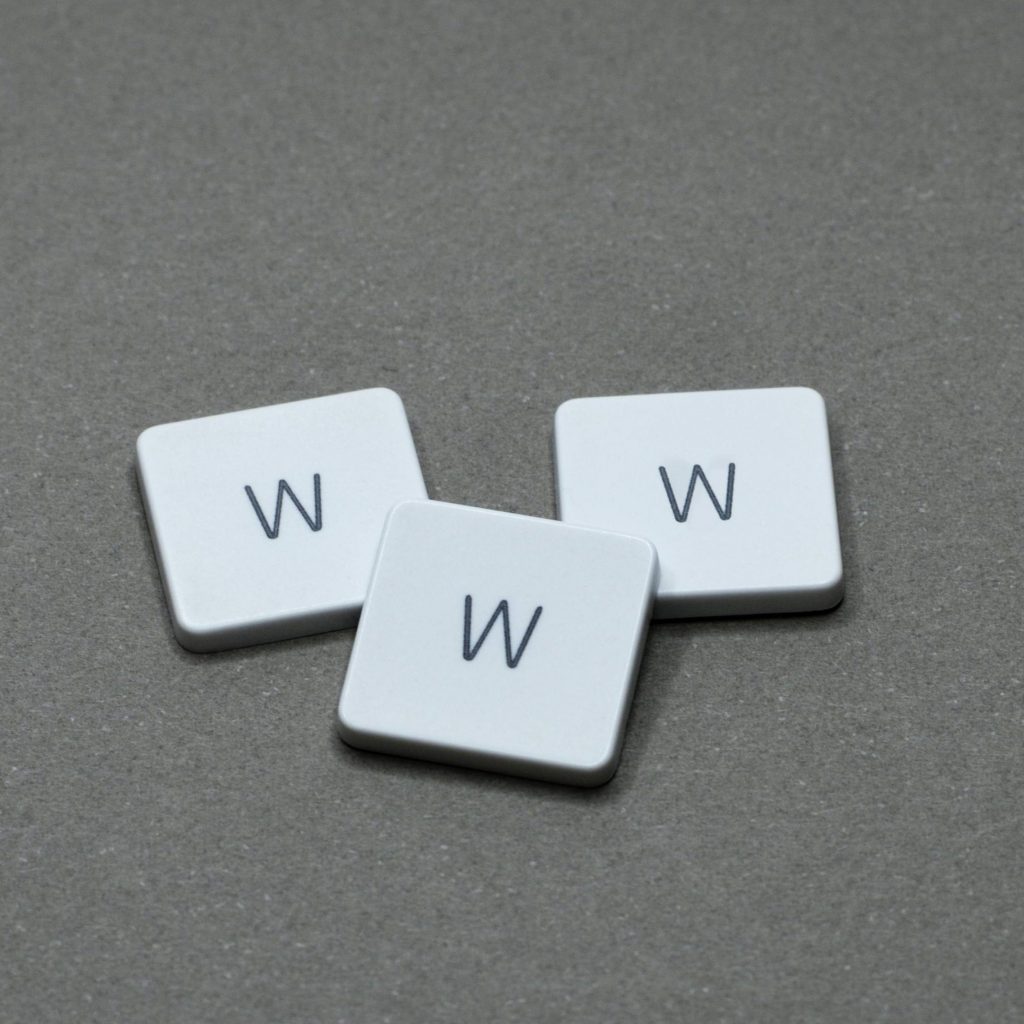 Three white letter tiles with 'W' on a gray surface, minimalist design